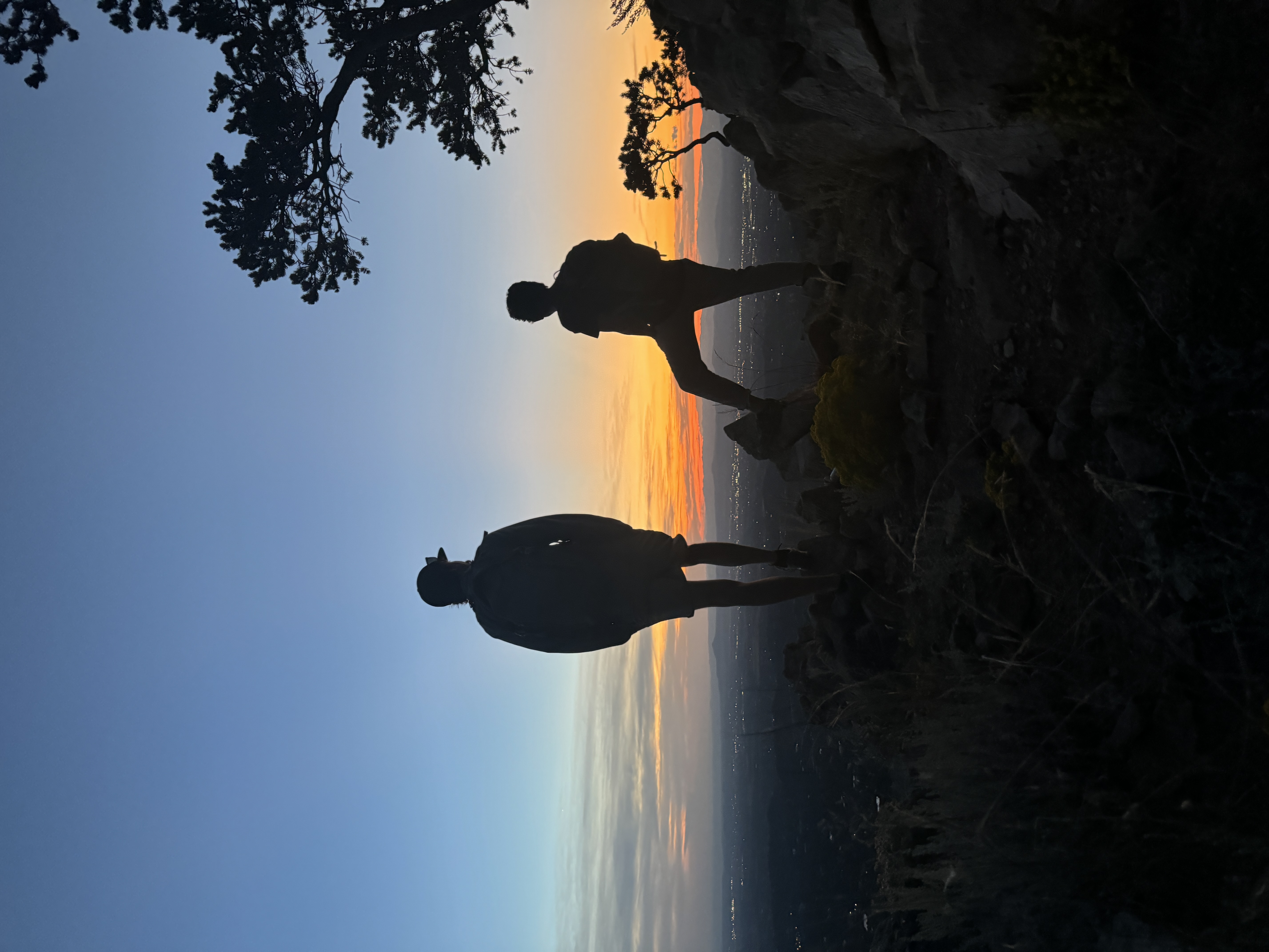 Two silhouettes on ridge at sunset